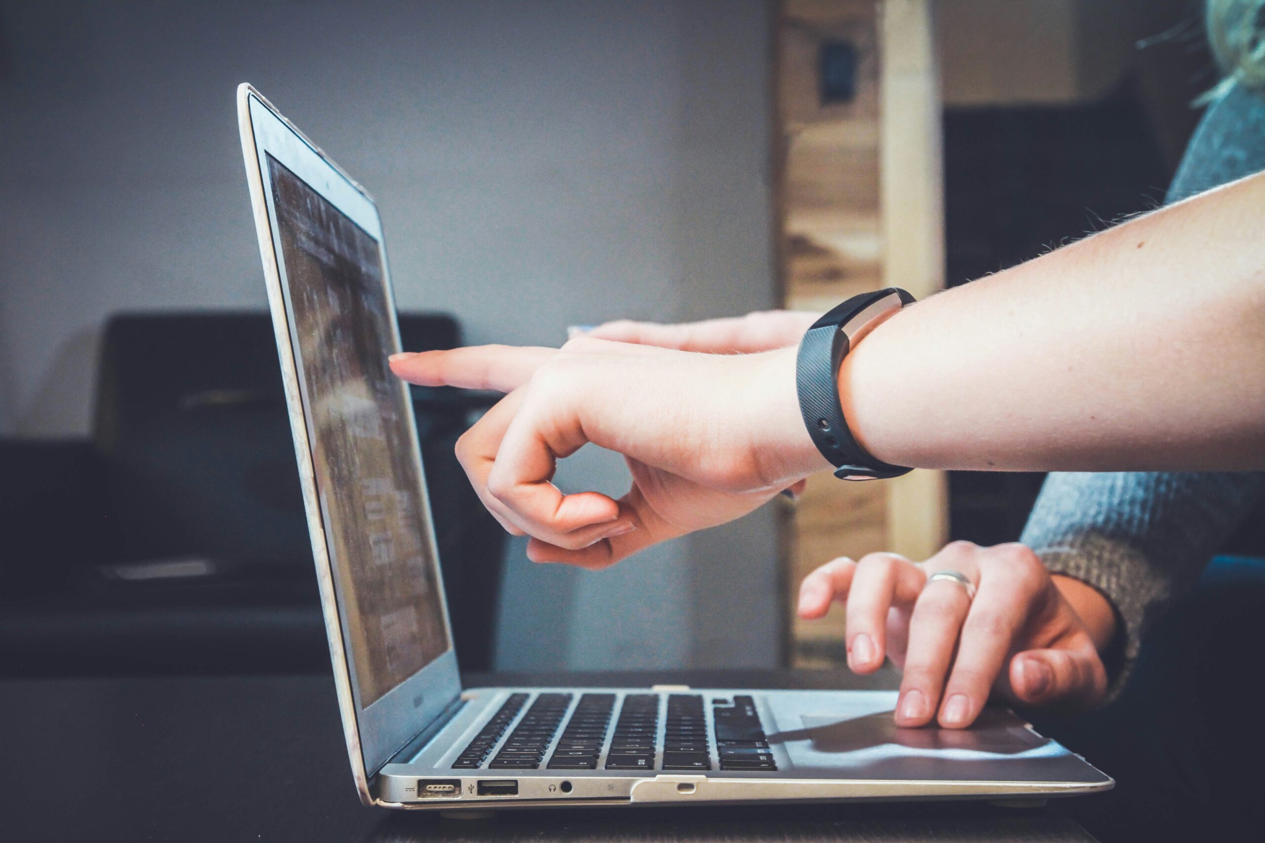 Two hands pointing to a laptop screen